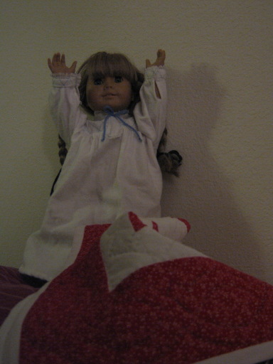 Kirsten is in bed, hands up, very scared.