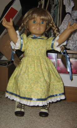 In front of her clothes storage, Kirsten wears a handmade yellow dress with lace and light blue ribbon trim.