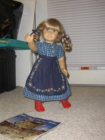 Kirsten is wearing her blue checked On the Trail dress with her embroidered apron