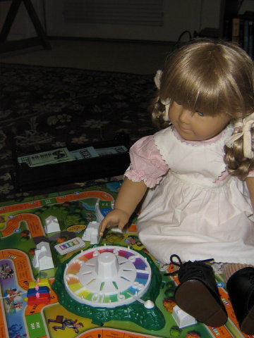 Kirsten has to sit on the game board to spin the wheel.