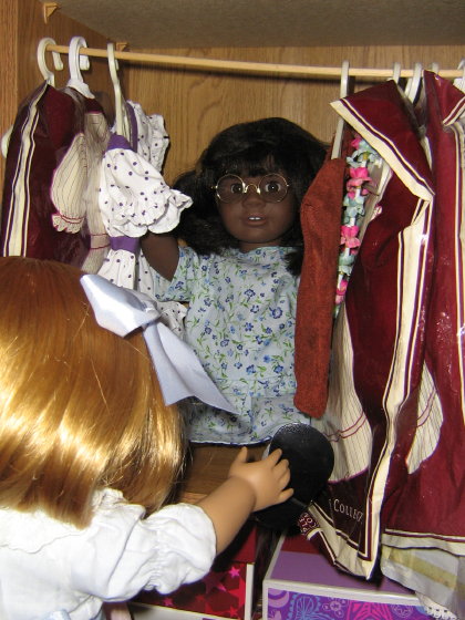 There is a dark-skinned doll with glasses and short hair behind the clothes!